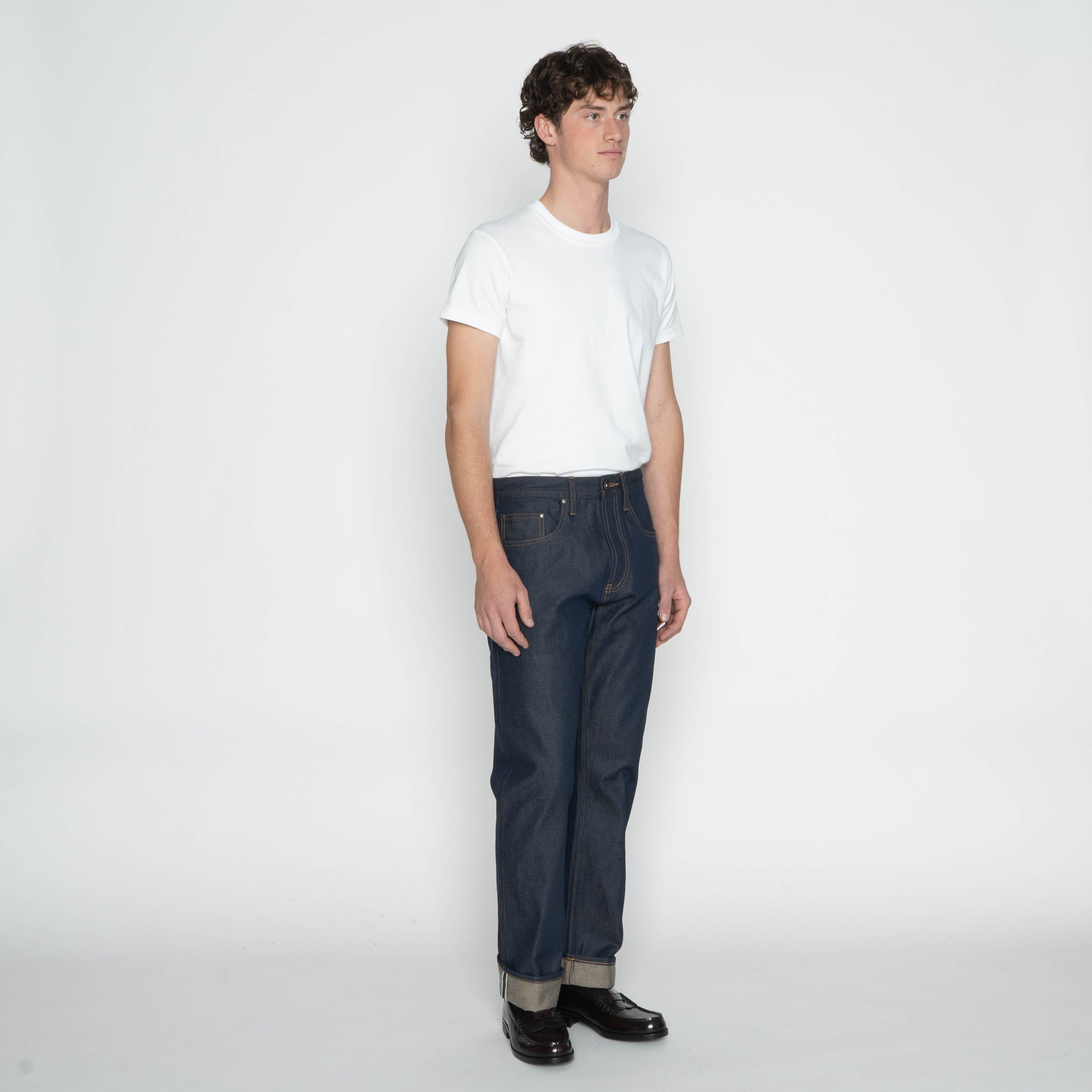 Person wearing a white t-shirt and dark jeans on a plain background